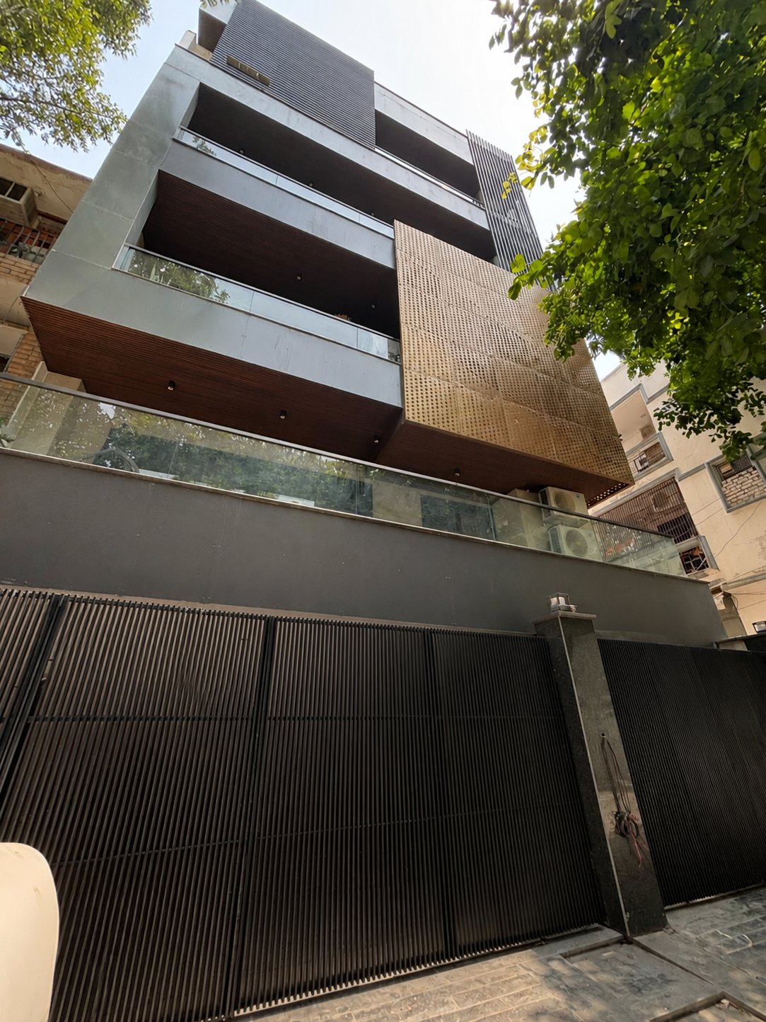 Coin Matrix: a residence faced with overlapping circular metal discs arranged in a dense matrix, set against plain wall surfaces.